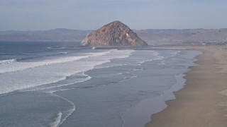 AXSF03_001 - 5K aerial stock footage flying low over the beach and ocean waves toward Morro Rock, Morro Bay, California
