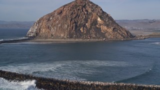 AXSF03_002 - 5K aerial stock footage tilt from ocean waves to reveal breakwater and Morro Rock, Morro Bay, California