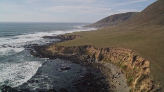 AXSF03_018 - 5K aerial stock footage of flying over a hill to follow the coastline, Harmony, California
