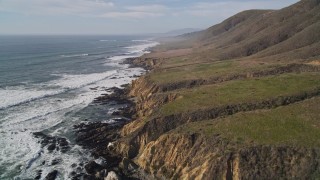 AXSF03_023 - 5K aerial stock footage tilt from crashing waves to coastline to reveal coastal cliffs, Cambria, California