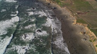 AXSF03_033 - 5K aerial stock footage tilt from ocean to reveal isolated beachfront mansion, Cambria, California