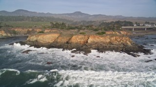 AXSF03_036 - 5K aerial stock footage of flying away from jagged coastal cliffs, San Simeon, California