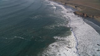 AXSF03_038 - 5K aerial stock footage of flying over waves rolling into the coast by Highway 1, San Simeon, California