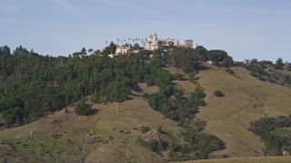 AXSF03_047 - 5K aerial stock footage of flying over rocky hillside, Hearst Castle in the distance, San Simeon, California