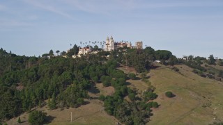 AXSF03_051 - 5K aerial stock footage of a wide view of Hearst Castle, eclipsed by a hill, San Simeon, California