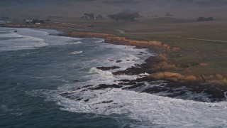 AXSF03_057 - 5K aerial stock footage pan across waves and coastline to reveal lonely oceanfront home, San Simeon, California