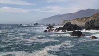 AXSF03_059 - 5K aerial stock footage of flying over rock formations and waves off the coast, San Simeon, California