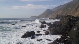 AXSF03_065 - 5K aerial stock footage fly low over waves, rock formations, pan to reveal coastal cliffs, San Simeon, California