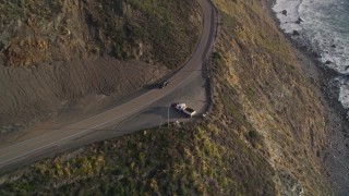 AXSF03_071 - 5K aerial stock footage of tracking a black SUV on Highway 1, above coastal cliffs, Big Sur, California