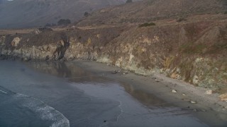 AXSF03_081 - 5K aerial stock footage fly over deserted beach at the base of cliffs, Big Sur, California