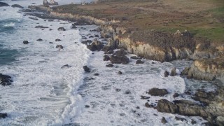 AXSF03_082 - 5K aerial stock footage tilt from ocean waves, approach rugged coastal cliffs, rock formations, Big Sur, California