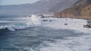 AXSF03_084 - 5K aerial stock footage of flying over tall waves, approaching coastal rock formations, Big Sur, California