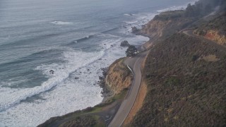 AXSF03_087 - 5K aerial stock footage of tilting from Highway 1 coastal road to cliffs to the coastline, reveal campground, Big Sur, California