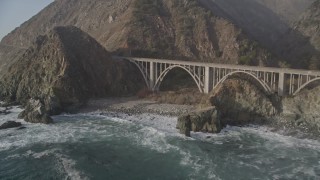 AXSF03_092 - 5K aerial stock footage of flying over ocean kelp to reveal small bridge on Highway 1 and cliffs, Big Sur, California
