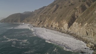 AXSF03_100 - 5K aerial stock footage of flying low over the ocean past coastal cliffs, Big Sur, California