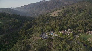 AXSF03_102 - 5K aerial stock footage of flying over Ventana Inn & Spa hotel, reveal highway through forest, Big Sur, California