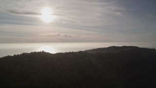 AXSF03_105 - 5K aerial stock footage of the sun high over the Pacific Ocean, seen from the hills, Big Sur, California