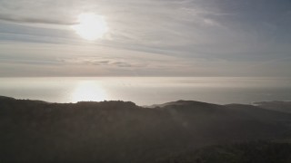 AXSF03_106 - 5K aerial stock footage of the sun high above the ocean, seen from the hills, Big Sur, California