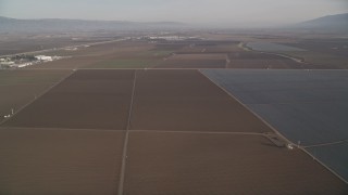 AXSF03_114 - 5K aerial stock footage of flying by a landscape of vast farm fields, Salinas, California
