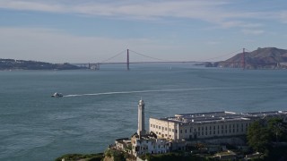 AXSF05_069 - 5K aerial stock footage tilt up to reveal and fly over Alcatraz, approach Golden Gate Bridge, San Francisco, California