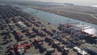 AXSF05_081 - 5K aerial stock footage flyby cargo containers to ships docked under cranes, Port of Oakland, Oakland, California