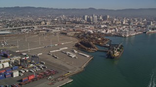 AXSF05_083 - 5K aerial stock footage flying by cargo cranes, shipping containers, cargo ships, Port of Oakland, Oakland, California
