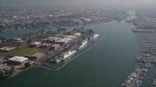 AXSF05_087 - 5K aerial stock footage pass ships docked at Coast Guard Island, approach warehouses and factories by the Oakland Estuary, California