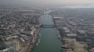 AXSF05_088 - 5K aerial stock footage fly over the Oakland Estuary toward bridges and factories, Oakland, California
