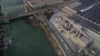 AXSF06_002 - 5K aerial stock footage of flying over estuary and warehouses, reveal factory, Fruitvale Bridge, Park Street Bridge, Oakland Estuary, California