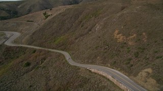 AXSF06_053 - 5K aerial stock footage of flying over coastal cliffs to reveal and follow Highway 1 at the base of mountains, Marin County, California