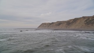 AXSF06_059 - 5K aerial stock footage of flying low over waves near coastal cliffs, Bolinas, California