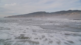 AXSF06_060 - 5K aerial stock footage of flying low over waves and rocky shallows near coastal cliffs, Bolinas, California
