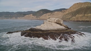 AXSF06_063 - 5K aerial stock footage of flying low over ocean panning across coastal cliffs to reveal and orbit rock formations, Bolinas, California
