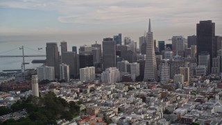 AXSF06_082 - 5K aerial stock footage approach famous Coit Tower, with Golden Gate Bridge in the distance, and orbit to reveal Downtown San Francisco, California