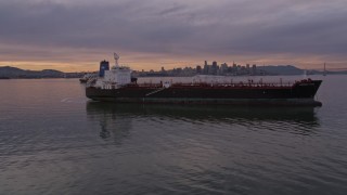 AXSF07_001 - 5K aerial stock footage tracking an oil tanker in San Francisco Bay, and reveal the city's skyline in the distance at sunset, California