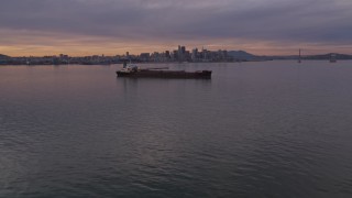 AXSF07_002 - 5K aerial stock footage fly over an oil tanker in San Francisco Bay, and tilt to the city's skyline in the distance at sunset, California