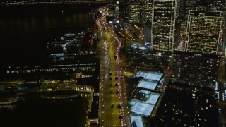 AXSF07_026 - 5K aerial stock footage following the Embarcadero between Ferry Building and Downtown San Francisco skyscrapers, California, night