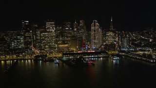 AXSF07_083 - 5K aerial stock footage of flying away from the Ferry Building to reveal Downtown San Francisco skyscrapers at night, California