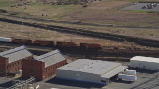 AXSF08_093 - 5K aerial stock footage track a train passing by industrial buildings, Bay Point, California