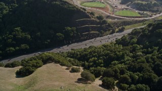 AXSF09_010 - 5K aerial stock footage of Highway 24 freeway through hills, tilt to soccer fields, Orinda, California