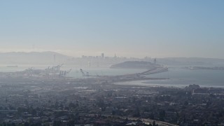 AXSF09_014 - 5K aerial stock footage a wide hazy view of Port of Oakland, Bay Bridge, and Downtown San Francisco skyline, California