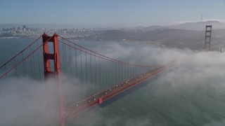 AXSF09_039 - 5K aerial stock footage fly through fog over Marin Hills, reveal famous and iconic Golden Gate Bridge and the distant San Francisco skyline, California