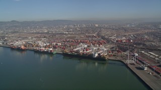 AXSF09_066 - 5K aerial stock footage pan across the Port of Oakland to approach cargo cranes, California