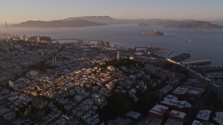 AXSF10_025 - 5K aerial stock footage of flying by Coit Tower in North Beach with a view of San Francisco Bay, California, sunset