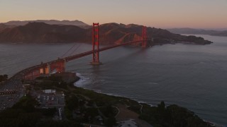 AXSF10_051 - 5K aerial stock footage pan across Highway 101 in Presidio, reveal Golden Gate Bridge, San Francisco, California, sunset