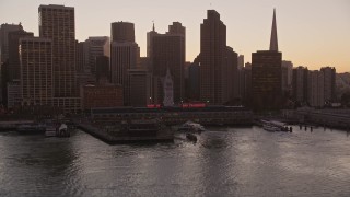 AXSF10_069 - 5K aerial stock footage tilt from the bay to reveal the Ferry Building and Downtown San Francisco skyscrapers, California, sunset