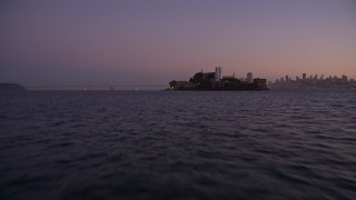 AXSF10_086 - 5K aerial stock footage of approaching Alcatraz at a low altitude, San Francisco, California, twilight