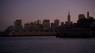 AXSF10_091 - 5K aerial stock footage of flying low over the bay by Coit Tower and Downtown San Francisco skyline, California, twilight