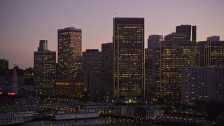 AXSF10_092 - 5K aerial stock footage fly low by piers and ascend toward skyline of Downtown San Francisco, California, twilight