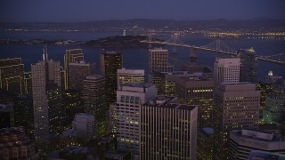AXSF10_098 - 5K aerial stock footage tilt from city streets to reveal skyscrapers in Downtown San Francisco and Bay Bridge, California, night